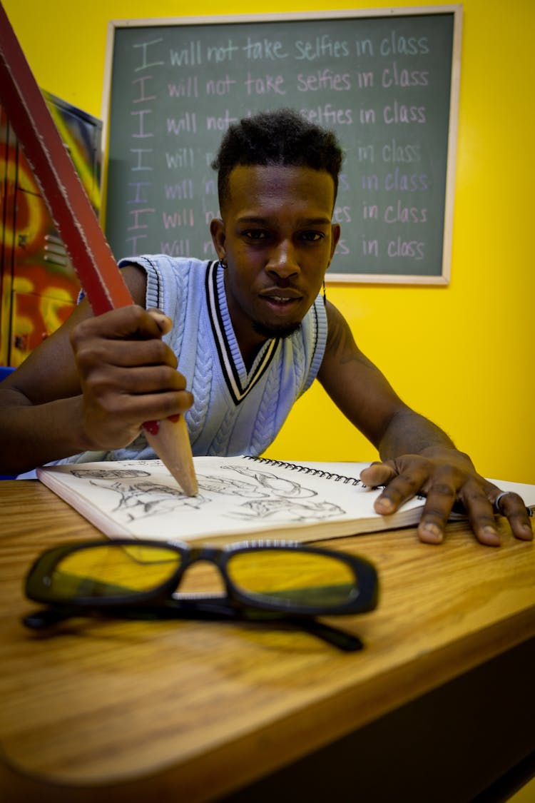 Man Writing With A Pencil In Class