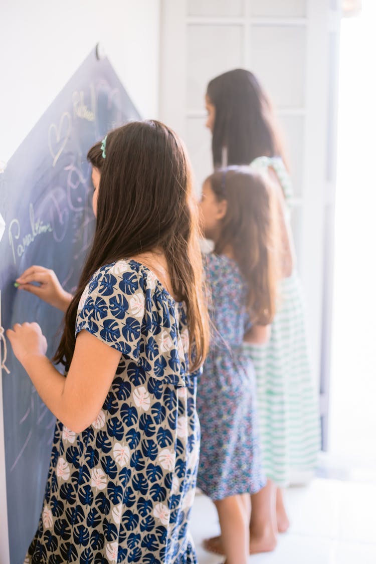 Standing Girls Writing On Blackboard