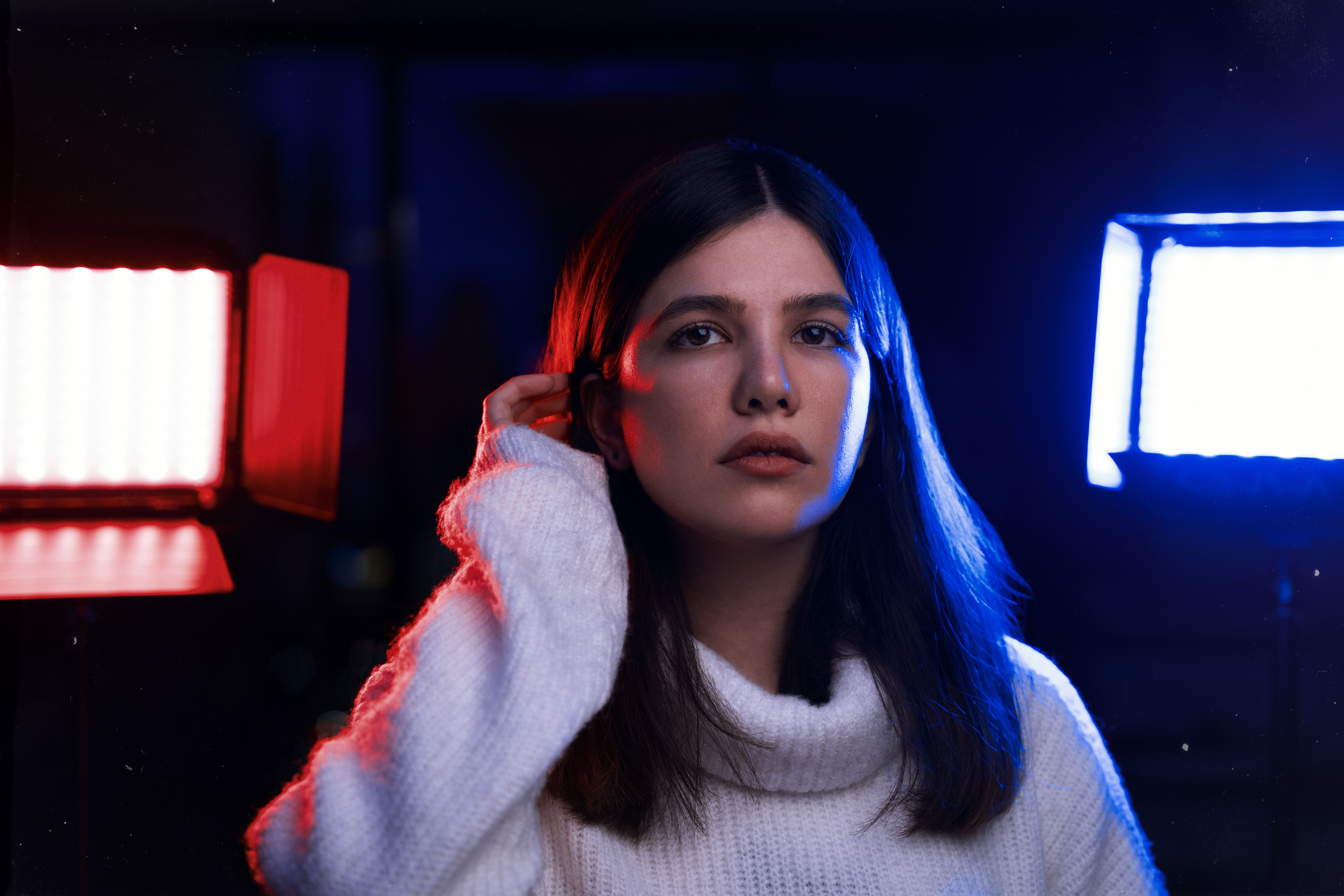 Elegant fashion portrait with dramatic blue and red lighting highlighting the model's features.