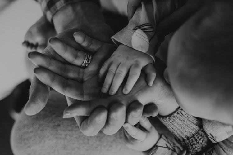 Black And White Photo Of Hands Of Adults And A Baby