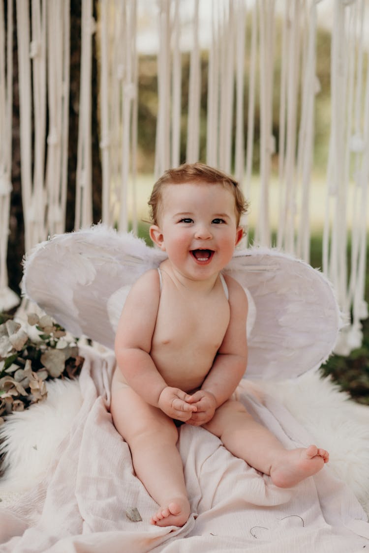 Portrait Of A Smiling Baby Wearing An Angels Wings