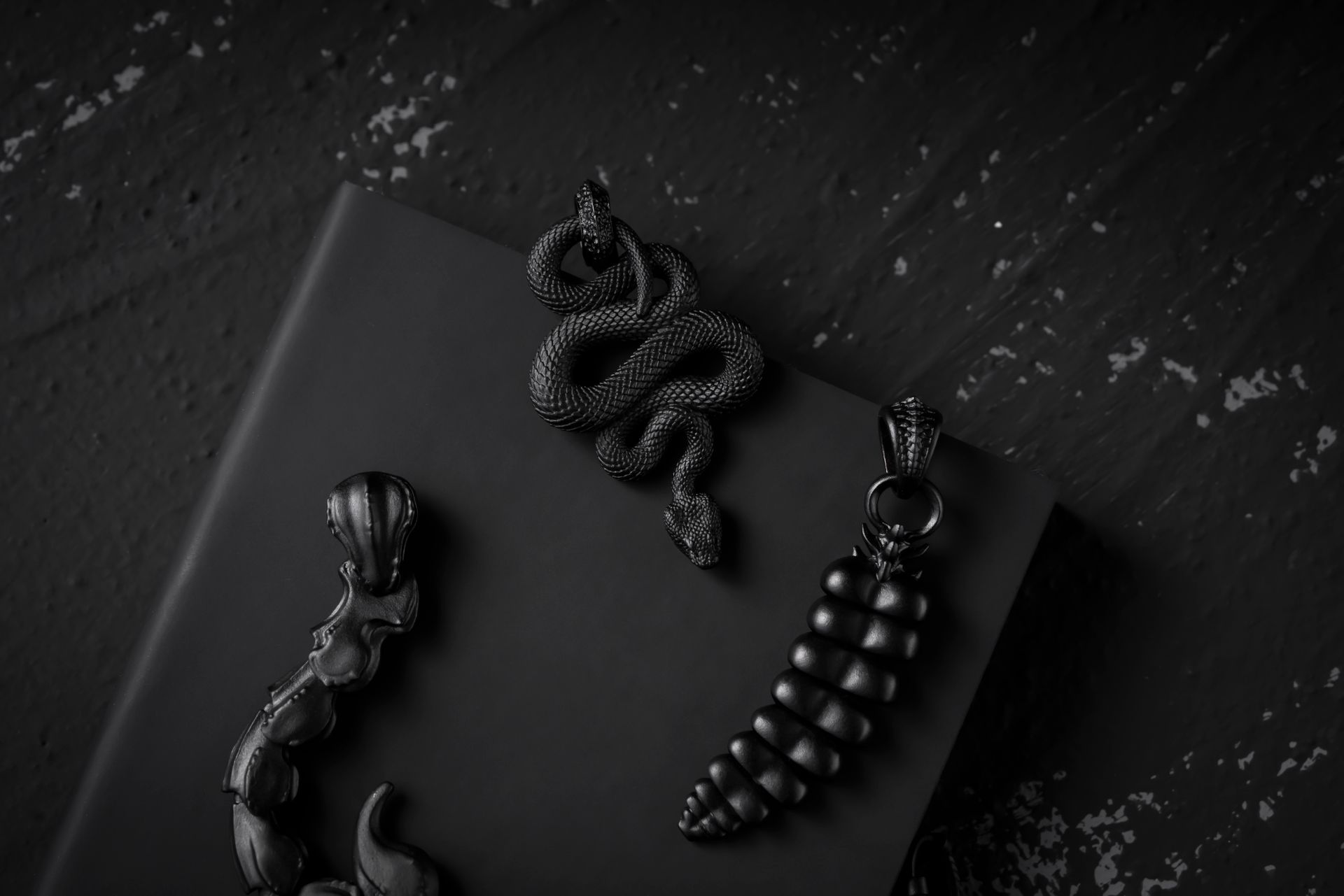 Intricately designed black snake jewelry displayed on a dark surface, showcasing elegance and detail.