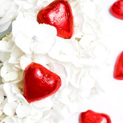 Red foil heart chocolates on white blossom — photo by Studio Naae on Pexels