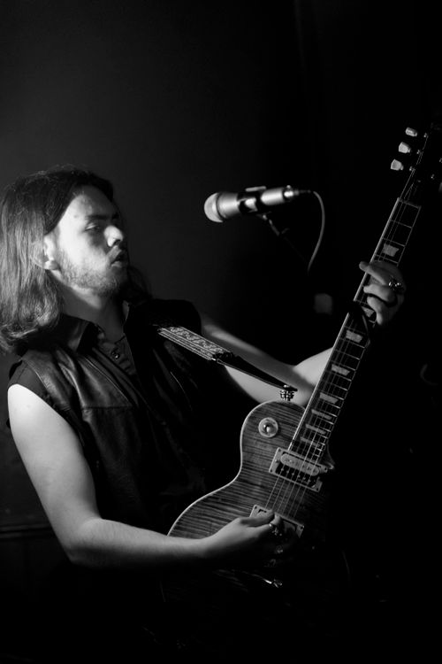 Free Dynamic black and white portrait of a guitarist playing passionately on stage with moody lighting. Stock Photo