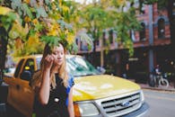 一位女士站在温哥华市区的街道上，身后是秋叶和一辆黄色汽车