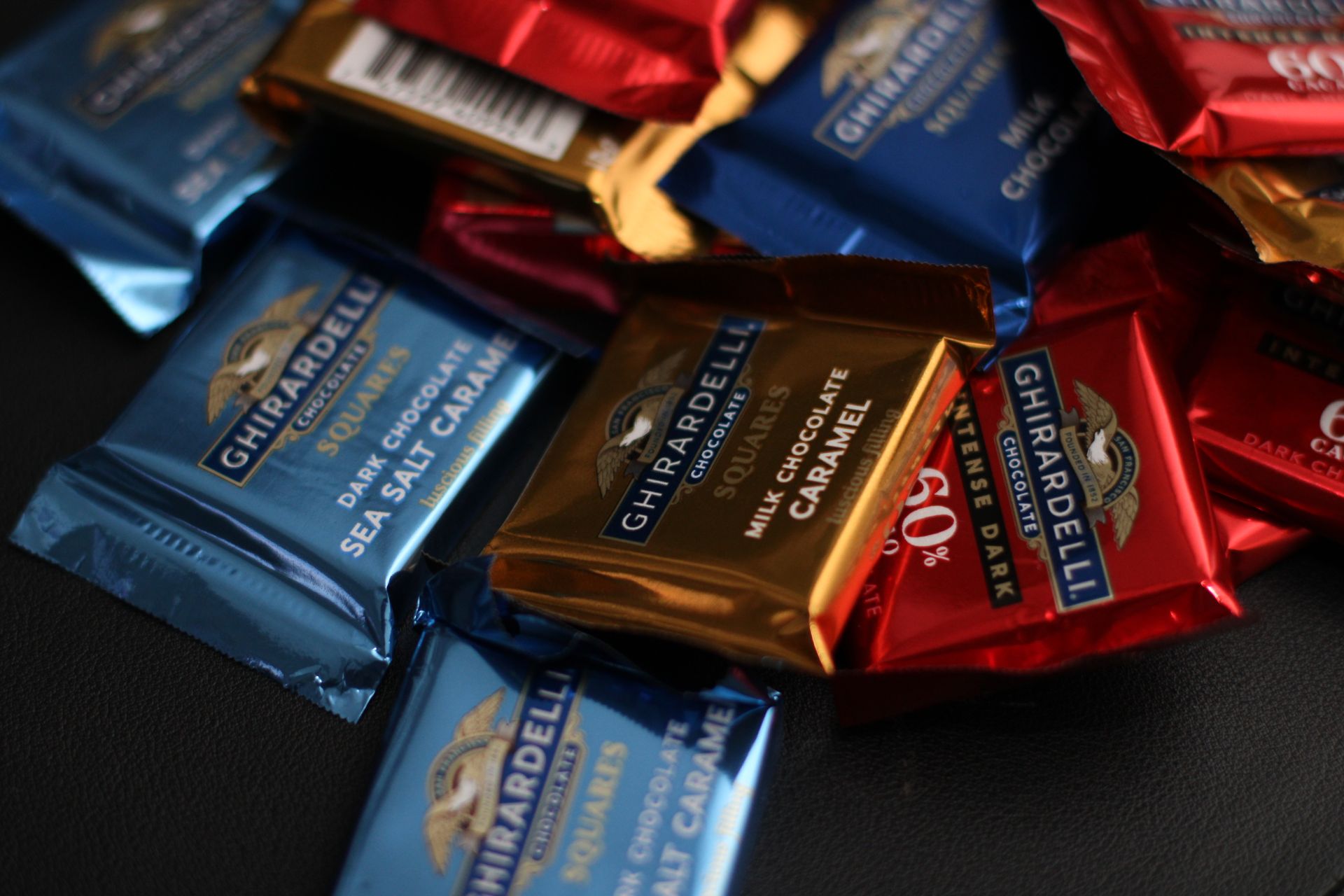 A close-up shot of a variety of Ghirardelli chocolate squares, including dark chocolate and milk chocolate caramel.