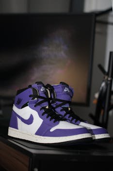 Purple and white high top Air Jordan sneakers on a display shelf indoors.