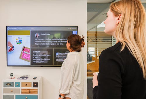 Women Standing in the Office and Looking at a TV Screen 