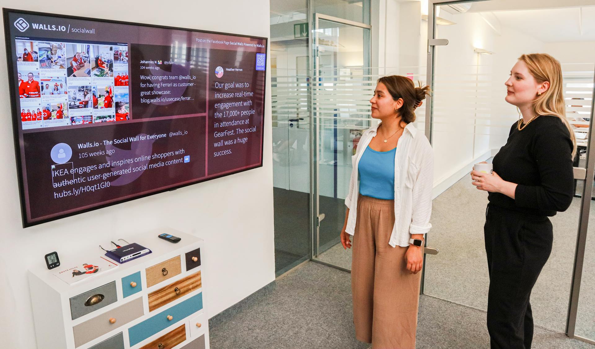 Two employees checking the company news on a screen at the office