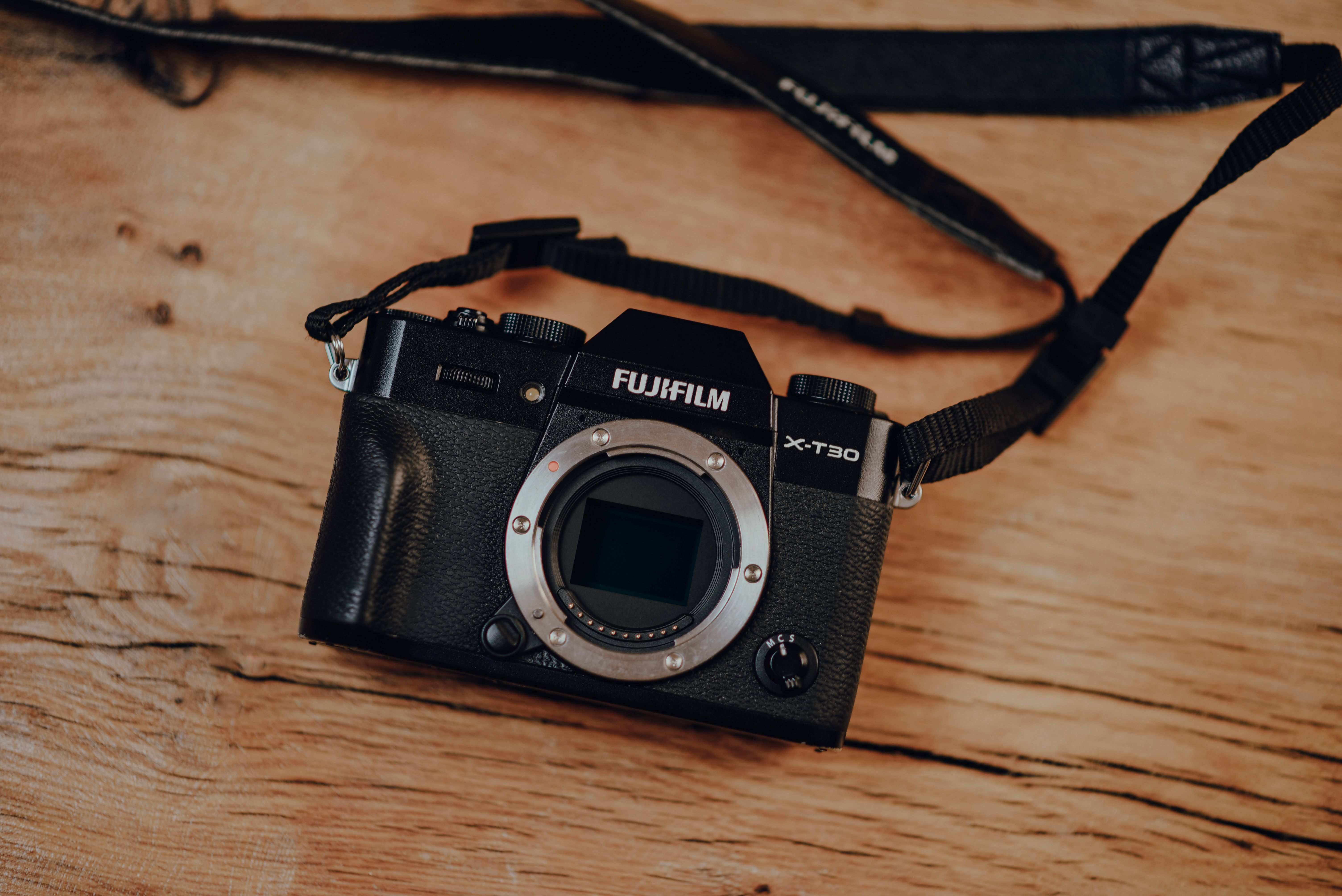 A Voigtlander Nokton 35mm f/0.9 lens is securely mounted on a sleek Fujifilm X-mount mirrorless camera, featuring a creamy, out-of-focus background.