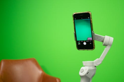 Close-up of a Smartphone Attached to a Stabilizer Recording a Green Background 