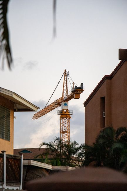 Photo by Griffin Wooldridge A construction crane stands tall amongst urban houses with a clear sky backdrop.