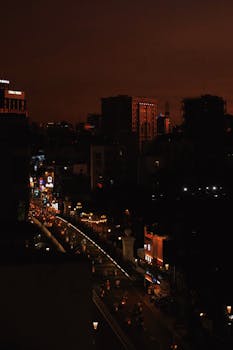 Dramatic nighttime city scene with bustling streets, bright lights, and urban architecture.