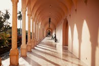 阳光走廊美丽宜人，拱门与雕像投下阴影，尽显建筑优雅