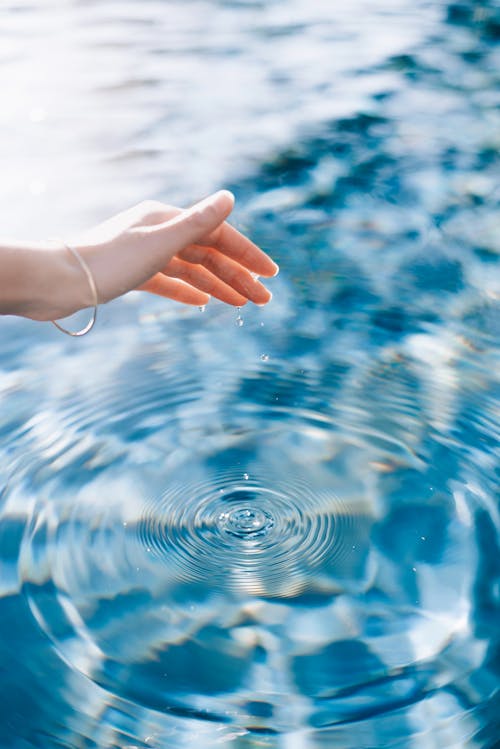 A person's hand is touching the water in a pool