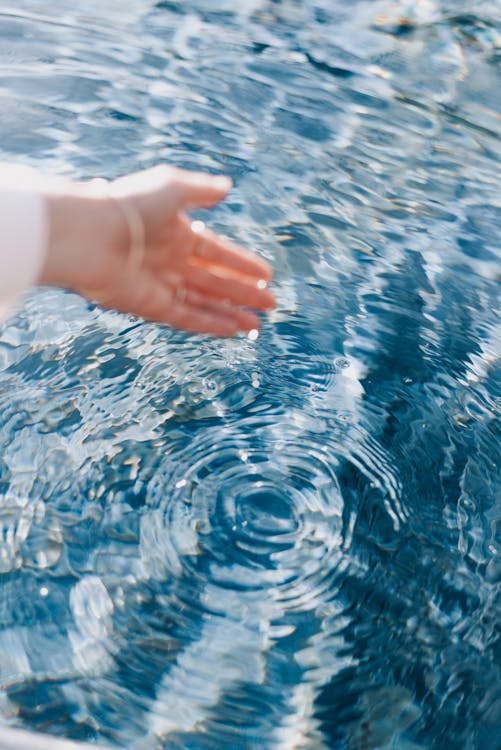 A person's hand is touching the water in a pool · Free Stock Photo