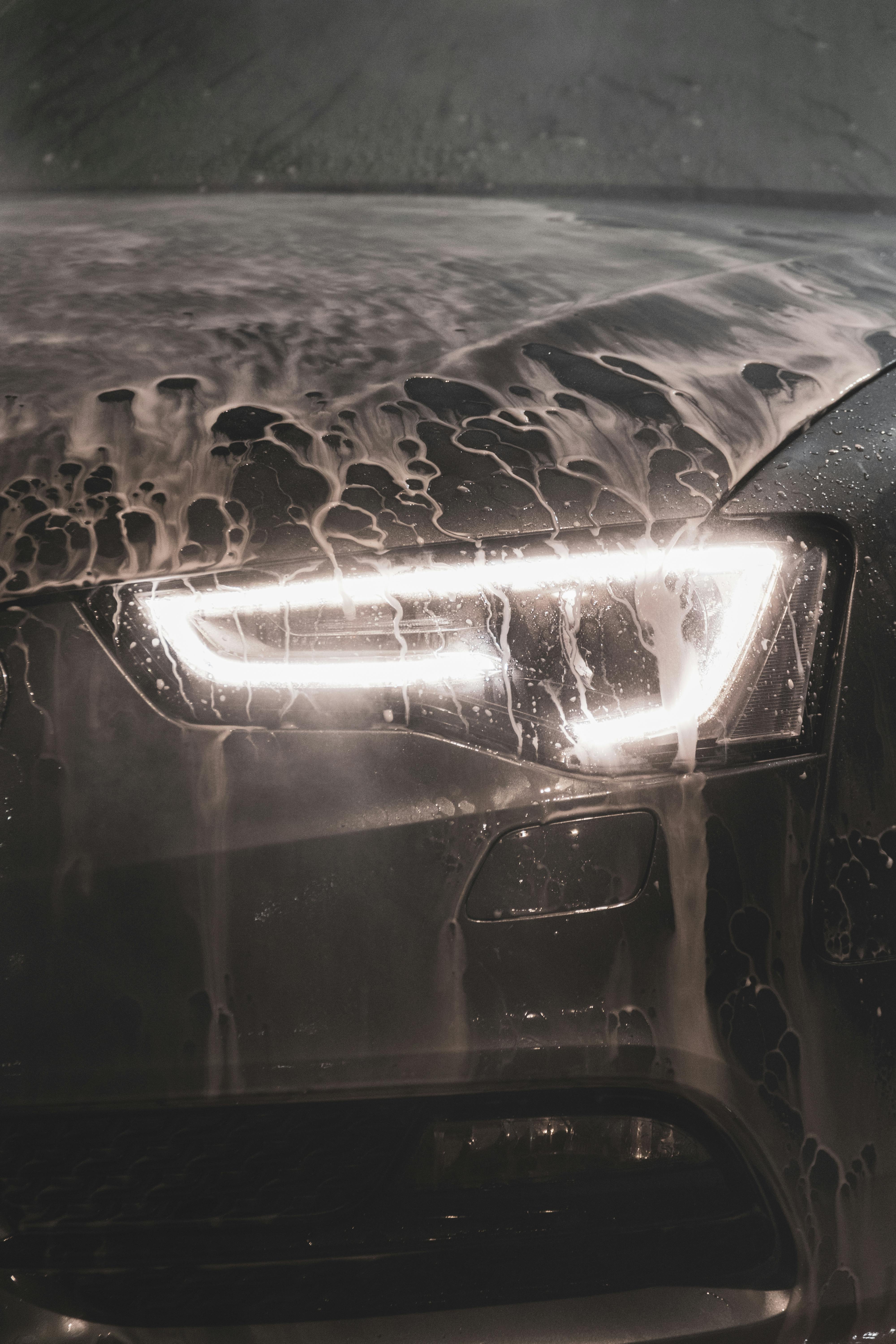 Closeup of an Audi A5 Headlight and Hood Covered in Foam at a Car Wash