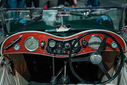 Close-up of a vintage car dashboard featuring wooden panel and classic gauges.