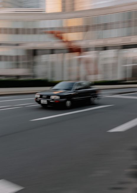 Blurred black car speeding through Shinjuku City, Tokyo, encapsulating urban movement and energy.