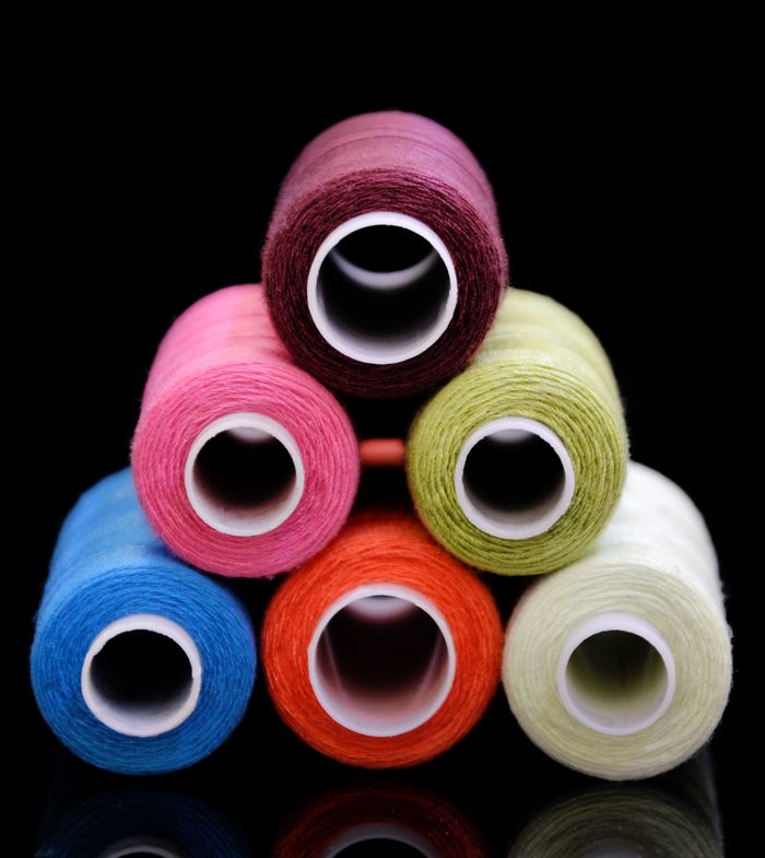 หลอดด้ายหลากสีวางซ้อนกันบนพื้นหลังสีเข้ม