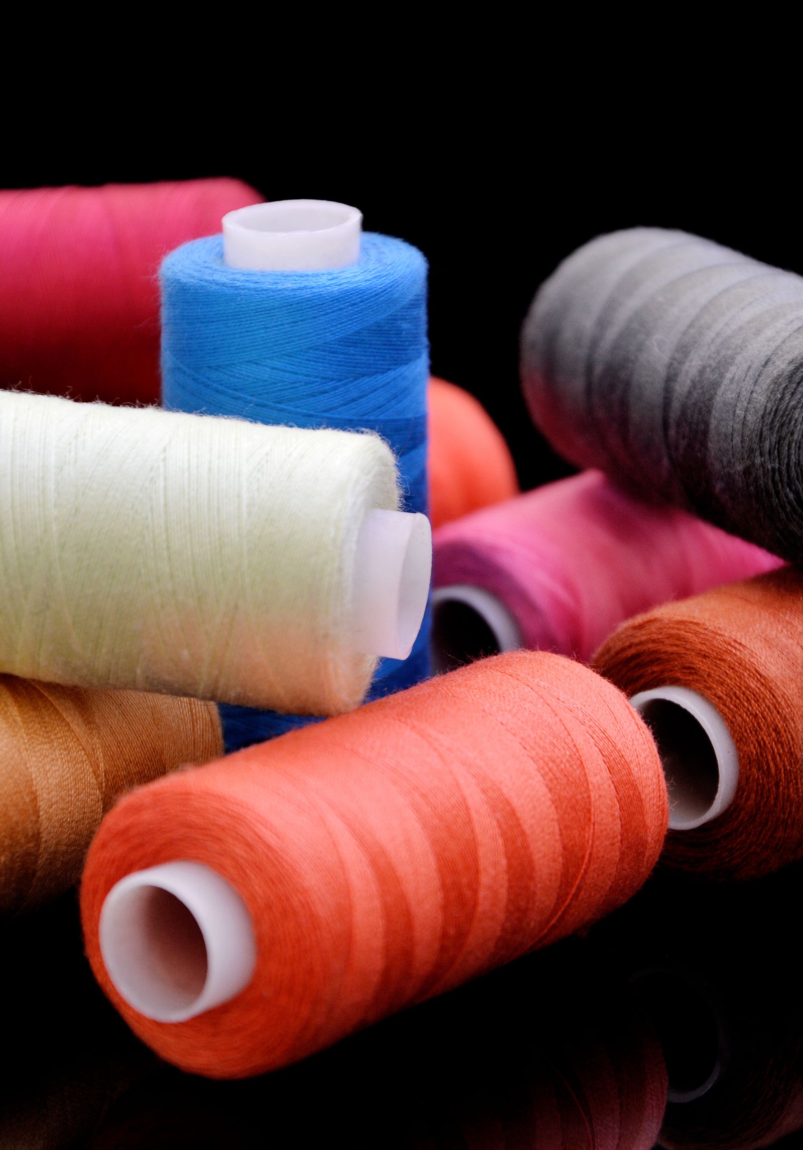 Stacked rolls and cones of waxed thread in a workshop