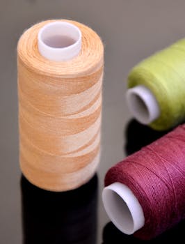 Close-up of colorful sewing threads on a glossy black surface, showcasing vibrant colors.