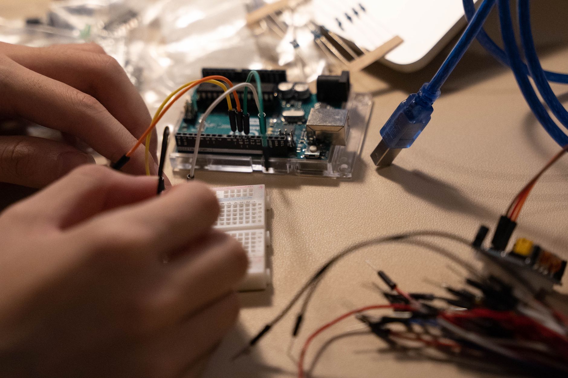 Close-up of hands assembling electronic components on a breadboard with wires.