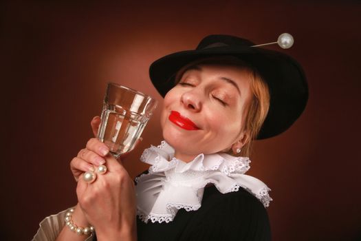 Elegant woman with closed eyes holding a glass, dressed in vintage fashion with pearls and hat.