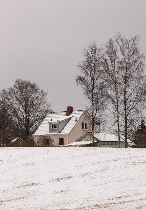 Free A peaceful winter scene featuring a secluded house surrounded by snow and trees. Stock Photo