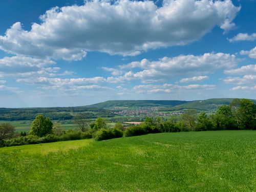 Free Tranquil view of green fields and rolling hills under a blue cloudy sky. Stock Photo