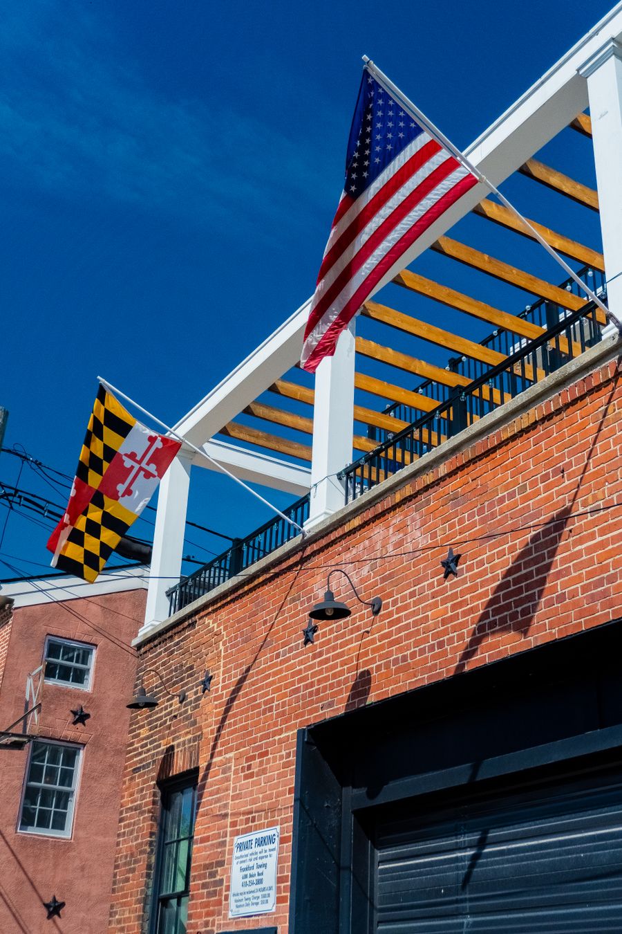 American and Maryland flags on a brick facade under a clear sky in Maryland