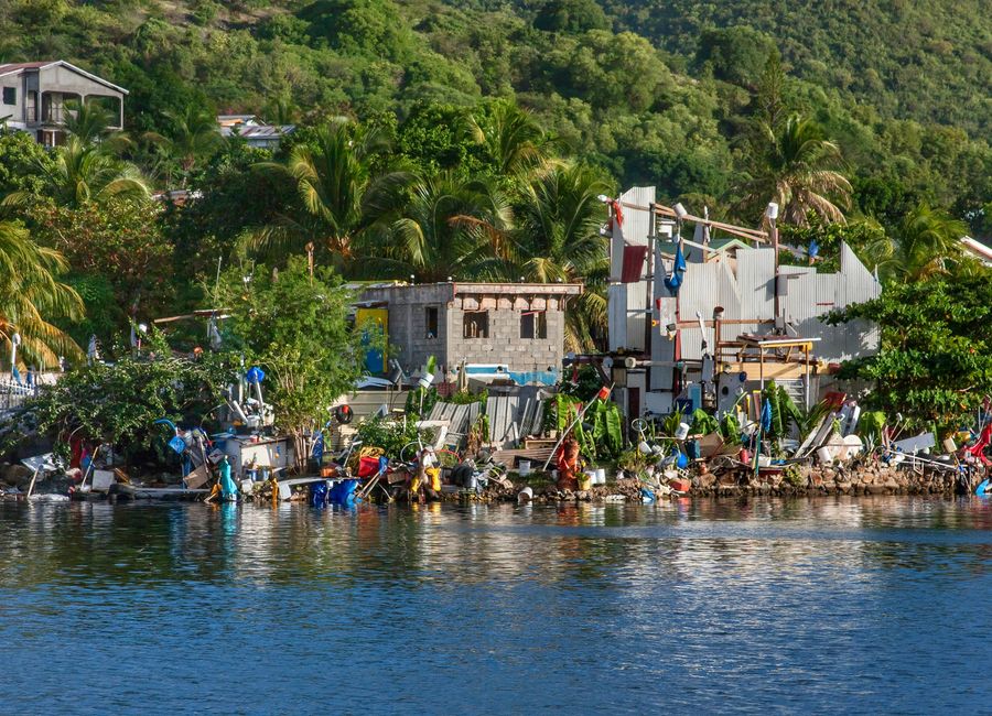 Picturesque waterfront scene in Sint Maarten with rustic buildings amidst lush greenery.