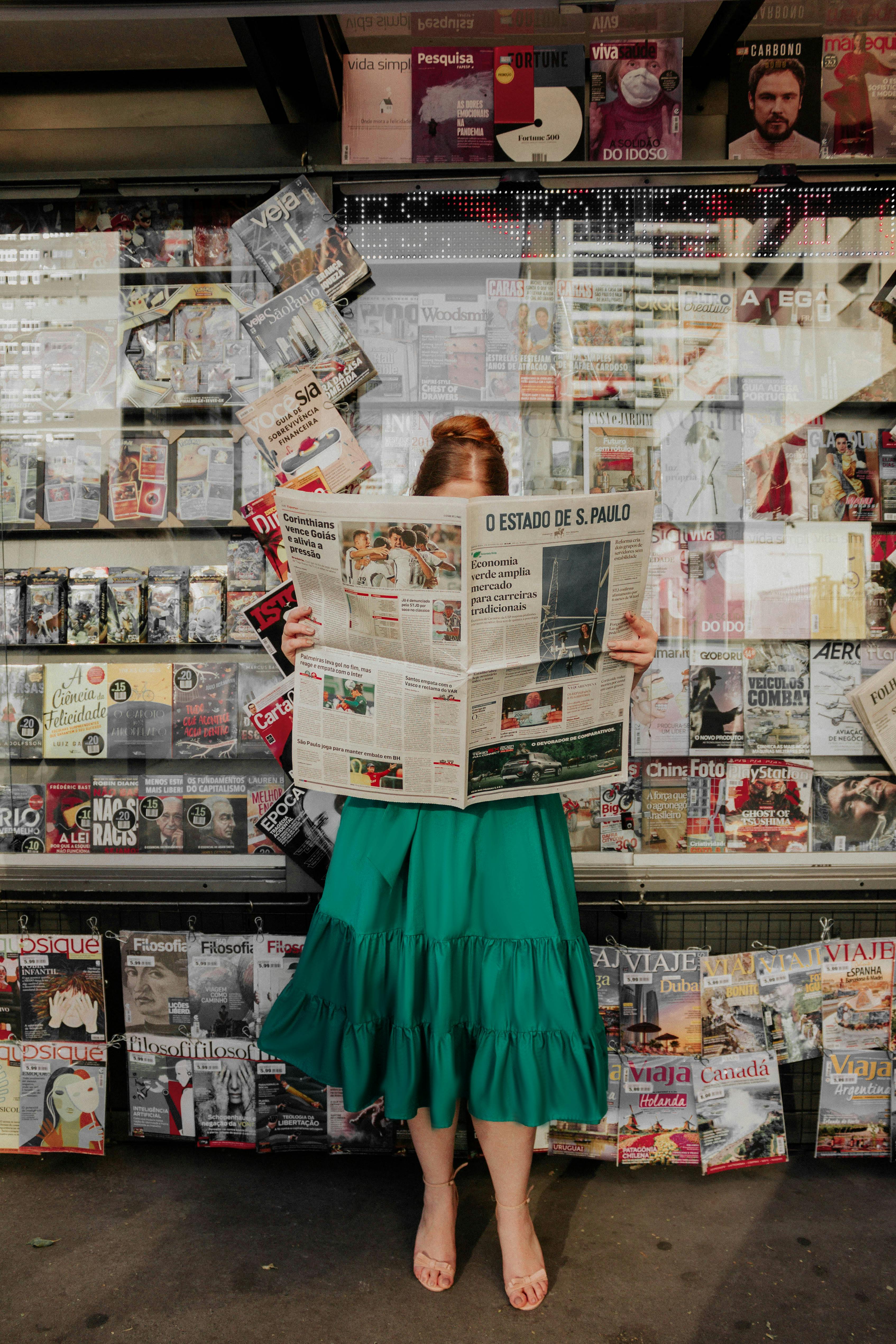 woman in dress reading newspaper near stand