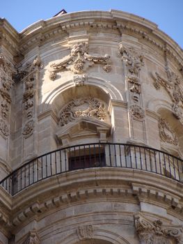 Close-up of decorative stone facade with railings in Málaga, Spain.