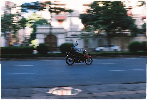 Blurred Motion of a Man on a Motorcycle on a City Street 