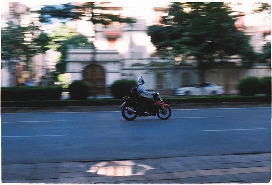 Motorcyclist speeding through a city street with blurred motion effect, showcasing urban transportation.