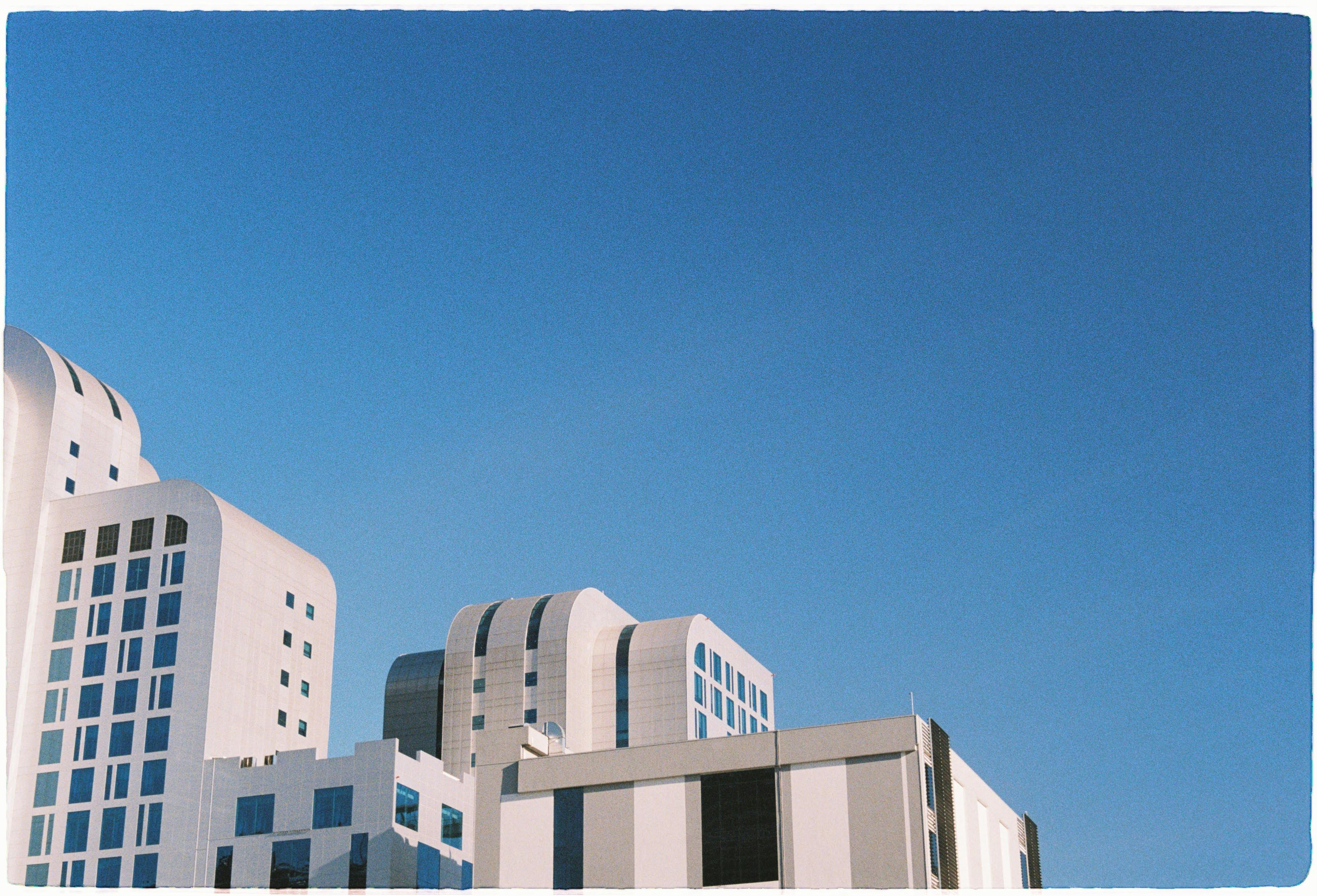 Contemporary urban architecture against a clear blue sky, showcasing sleek geometric design.