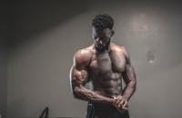 一位光着膀子的强壮男性健美运动员正在健身房展示肌肉和力量