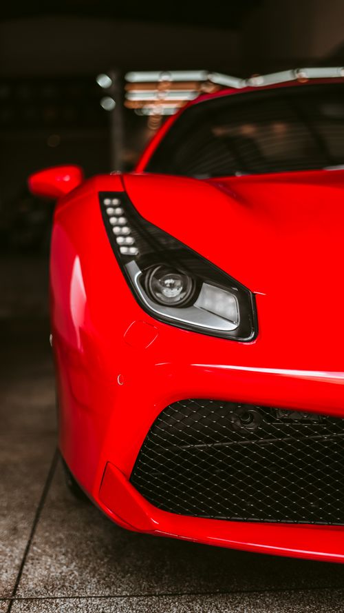 Free Close-up of a luxurious red sports car's front, showcasing sleek design and modern headlights. Stock Photo