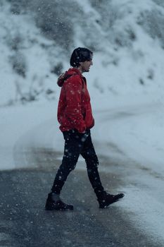 Portrait of a man in a red jacket walking through a snowy landscape during winter.
