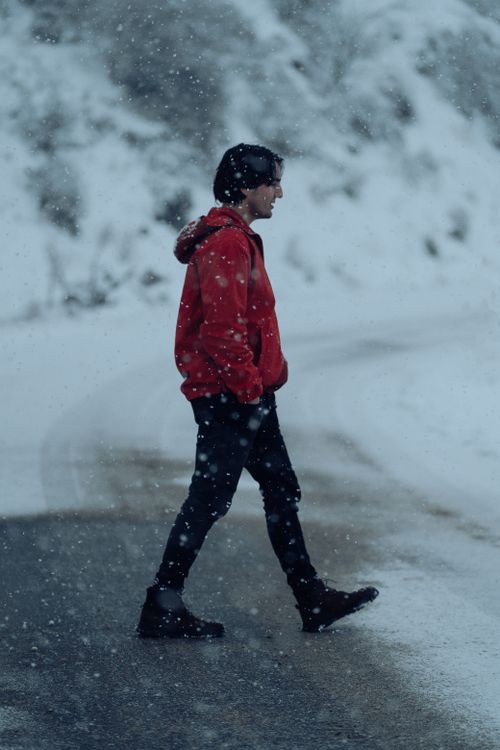Free Portrait of a man in a red jacket walking through a snowy landscape during winter. Stock Photo