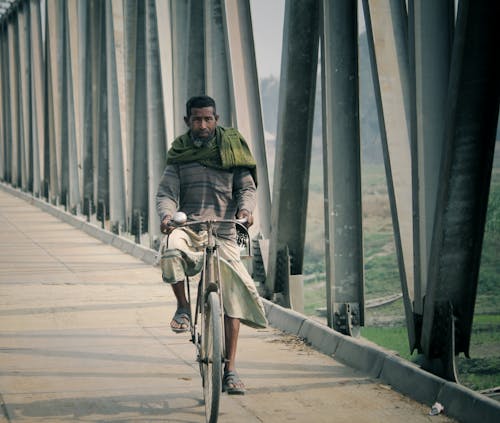 A Man Riding on a Bicycle on the Bridge 