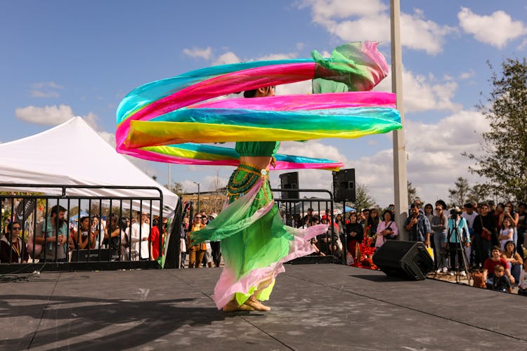 Audience Looking At A Woman In A Colorful Costume Dancing On Stage 