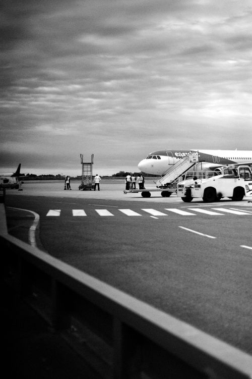 Free Grayscale image of an airplane and ground crew on the runway in Bordeaux, France. Stock Photo