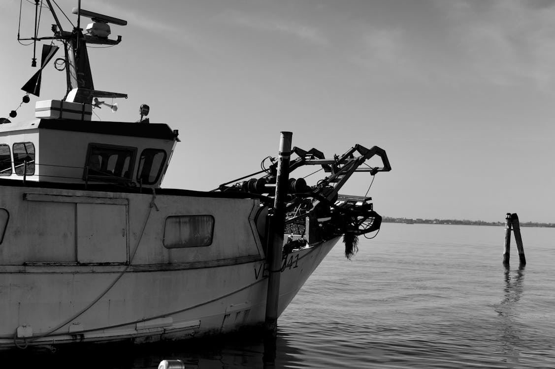 Grayscale Photo of Boat on Docked