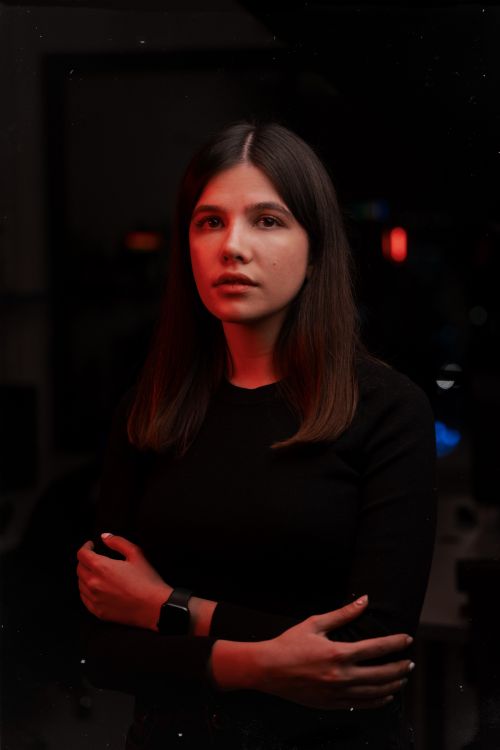 Free Captivating portrait of a woman with crossed arms in dramatic red lighting indoors. Stock Photo