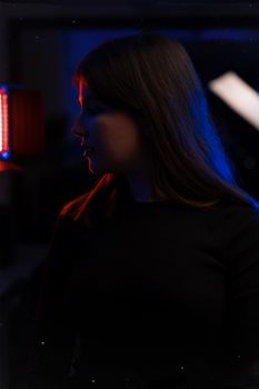 Silhouette portrait of a woman in low light with dramatic blue and red lighting.
