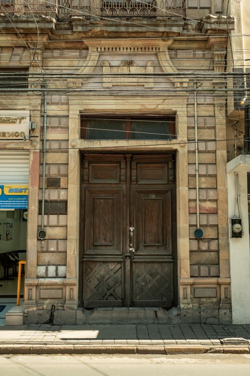 Free A vintage wooden door on an old building facade with textured stonework on a city street. Stock Photo