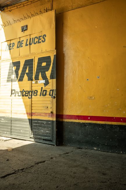 A bold yellow industrial warehouse entrance featuring vintage signage and a textured exterior surface.