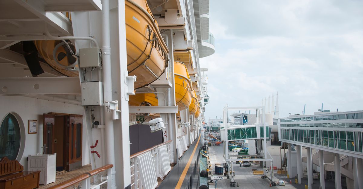 A detailed view of life boats on a docked cruise ship at a port, showcasing maritime safety equipment and infrastructure.